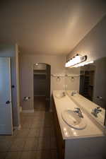 Bathroom with double vanity, tile patterned flooring, and a walk in closet