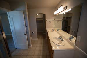 Full bath featuring double vanity, a spacious closet, and tile patterned flooring