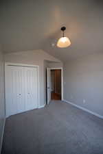 Unfurnished bedroom with lofted ceiling, carpet flooring, and a closet