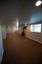 Below grade area with a wood stove, carpet flooring, and a textured ceiling
