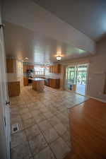 Kitchen with open floor plan, a center island, brown cabinetry, appliances with stainless steel finishes, and light countertops