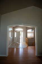 Foyer featuring wood finished floors, vaulted ceiling, and stairs