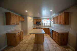 Kitchen with a kitchen island, recessed lighting, appliances with stainless steel finishes, light countertops, and light tile patterned flooring