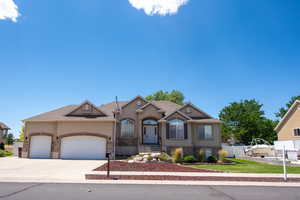 View of front of home featuring stucco siding, an attached garage, driveway, a shingled roof, and stone siding