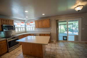 Kitchen featuring appliances with stainless steel finishes, healthy amount of natural light, light countertops, recessed lighting, and a textured ceiling