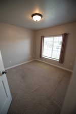 Unfurnished room with carpet flooring and a textured ceiling