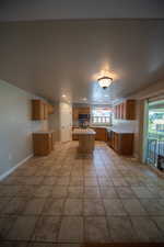 Kitchen with light countertops, a center island, brown cabinetry, and appliances with stainless steel finishes