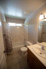 Full bath featuring tile patterned floors, vanity, shower / bath combination with curtain, and a textured ceiling
