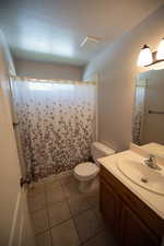 Bathroom featuring tile patterned floors, a textured ceiling, vanity, and curtained shower