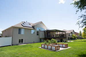 Back of property with solar panels, a fenced backyard, and a garden