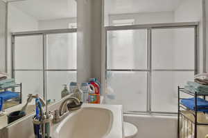 Full bathroom with bath / shower combo with glass door and vanity