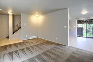 Empty room featuring tile patterned flooring, stairs, and carpet