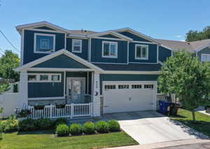 View of front facade featuring stone siding, a shingled roof, driveway, and a porch