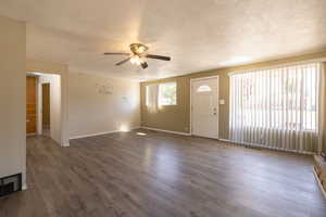 Unfurnished living room with wood finished floors, a ceiling fan, and a textured ceiling