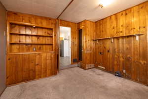 Carpeted empty room featuring wooden walls