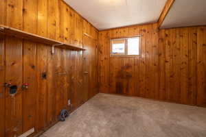 Carpeted empty room featuring wooden walls