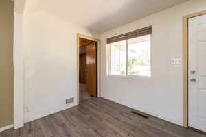 Spare room featuring dark wood-type flooring and baseboards