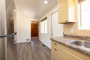 Kitchen featuring freestanding refrigerator, dark wood-style floors, backsplash, and recessed lighting