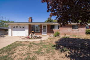 Ranch-style house featuring driveway, a garage, a chimney, and brick siding