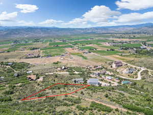 Aerial view of sparsely populated area with a mountainous background and property parcel outlined