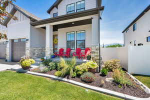 Craftsman-style house featuring stone siding, covered porch, board and batten siding, a 3-car garage, and driveway