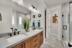 Primary Bathroom with marble finish flooring, a marble finish shower, and double vanity.