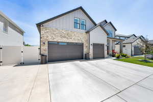View of front of property featuring board and batten siding, a gated RV parking, stone siding, driveway, and a 3-cargarage