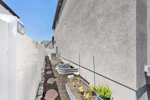 View of side of home featuring stucco siding and a garden