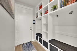 Mudroom featuring coat rack, storage, light wood finished floors