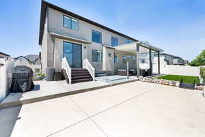 Rear view of house featuring a patio area, stucco siding, and a fenced backyard, faux grass, awning and hot tub patio.