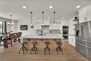 Kitchen featuring Kitchen aide stainless steel appliances, recessed lighting, tasteful backsplash, light countertops, and light wood-style floors