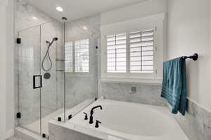 Primary suite  bathroom with an oversized garden bath, a glass marble finish shower, and recessed lighting