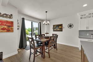 Dining area with over sized sliding glass door, light wood finished floors, a chandelier, and recessed lighting