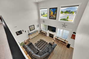 Living room with a towering ceiling, wood finished floors, healthy amount of natural light, 4.5" plantation shutters and programable Hunter Douglas shades for the upper windows.