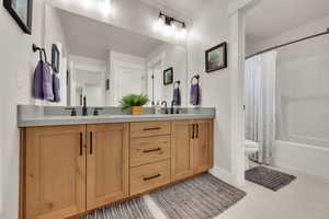 2nd Full bath featuring double vanity, shower / bath combo with shower curtain, and tile patterned flooring