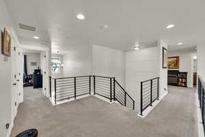 Hallway featuring an upstairs landing, recessed lighting, carpet, and modern iron railing.