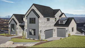 French country home featuring a mountain view, stone siding, a front lawn, driveway, and a metal roof