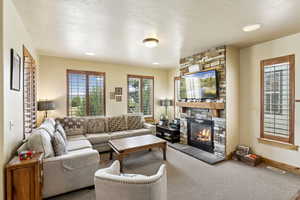 Carpeted living room with a fireplace and a textured ceiling