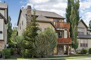 Back of house with a balcony, a shingled roof, and a chimney