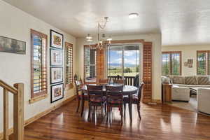 Dining room featuring healthy amount of natural light, a chandelier, wood finished floors, and a textured ceiling