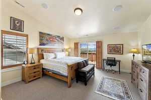 Bedroom featuring lofted ceiling, access to exterior, and light colored carpet