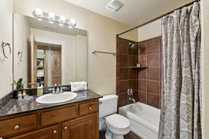 Bathroom featuring a textured wall, vanity, and shower / tub combo