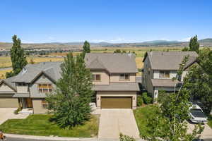 View of front facade with concrete driveway, a mountain view, an attached garage, a residential view, and a shingled roof