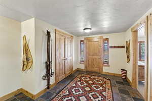 Foyer featuring a textured ceiling, healthy amount of natural light, and stone tile flooring