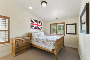 Carpeted bedroom with lofted ceiling and baseboards