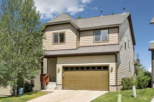 View of front of home with driveway, a shingled roof, and a garage