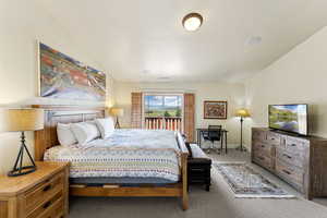 Carpeted bedroom featuring vaulted ceiling and access to exterior