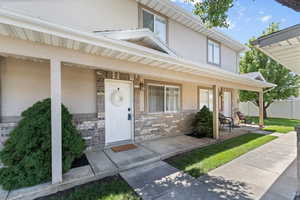 Property entrance featuring covered porch, stucco siding, stone siding, and brick siding