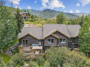 Rear view of property with a deck with mountain view, a shingled roof, board and batten siding, and outdoor dining space