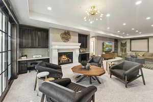 Living area featuring a tray ceiling, recessed lighting, light carpet, and a chandelier
